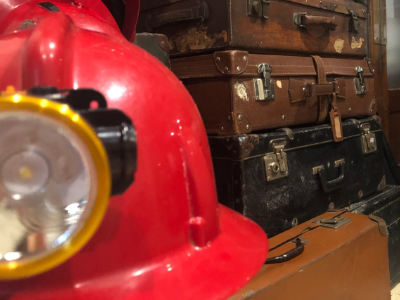 Casco de Minero con maletas antiguas de fondo